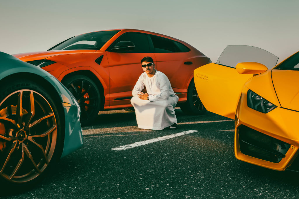 Professional photograph of a person posing in front of three Lamborghinis in Dubai