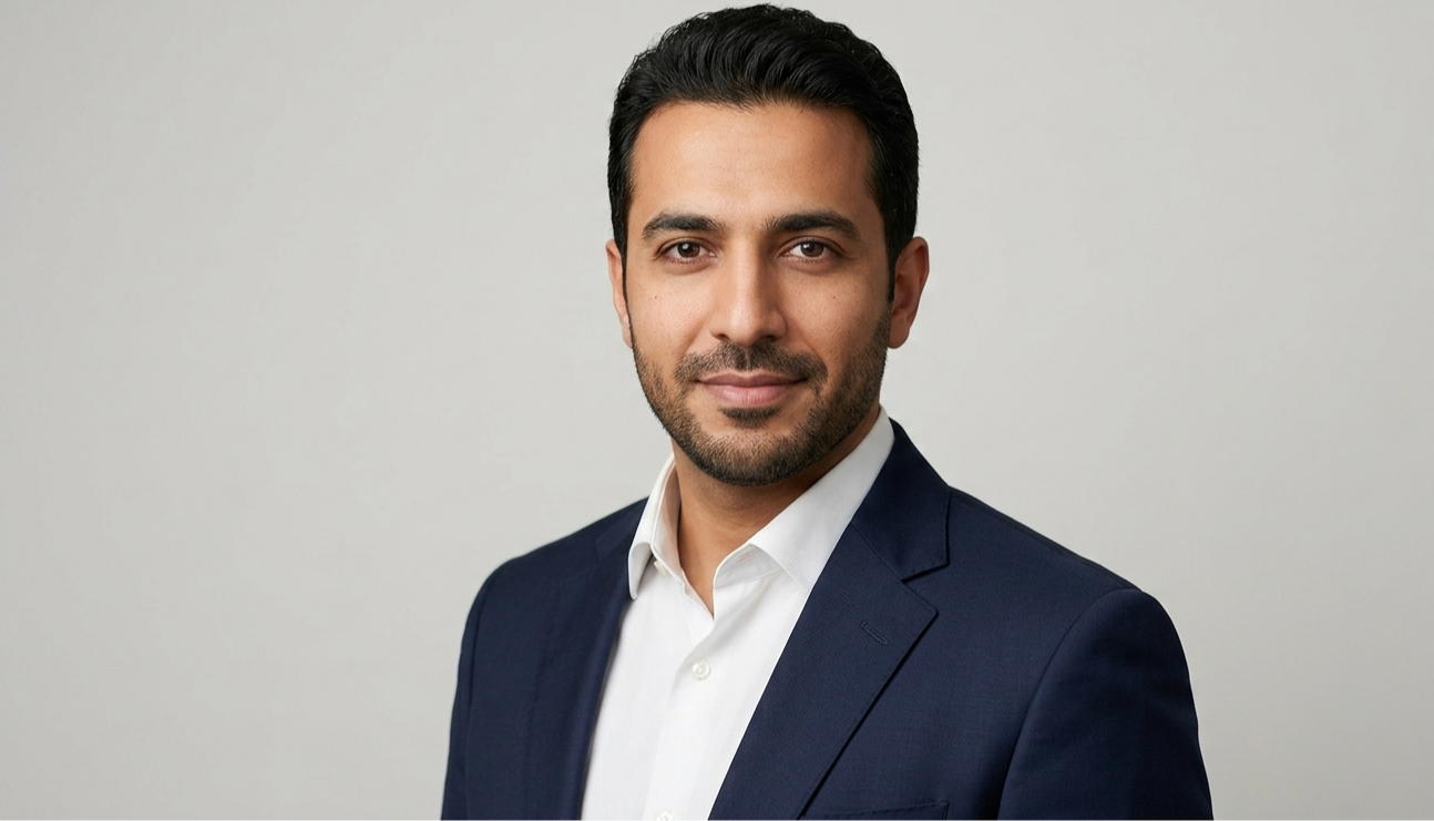 Professional corporate headshot of a man in a navy suit and white shirt against a neutral background.